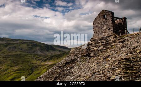 The ruins of an industrial building stand beside a slate tip at Croesor Quarry on Moelwyn Mawr mountain in Snowdonia, North Wales. Stock Photo