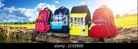 Colourful children schoolbags outdoors on the field Stock Photo