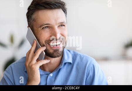 Closeup portrait of smiling handsome young businessman talking on mobile phone indoors Stock Photo
