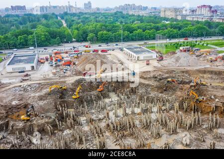 Working excavators on the site of a demolished building. Construction of a huge building in a pit near the city park cityscape, aerial top view Stock Photo