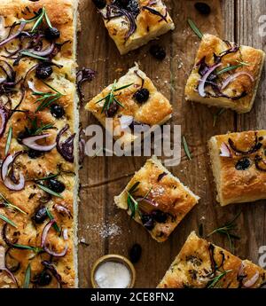 Focaccia with black olives and herbs on wooden table Stock Photo