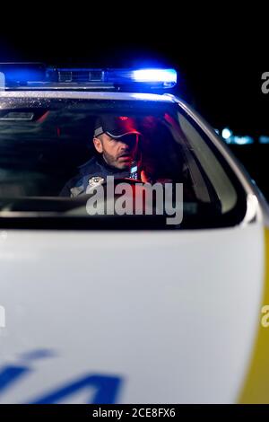 Male police officer sitting in parked automobile with siren light Stock Photo