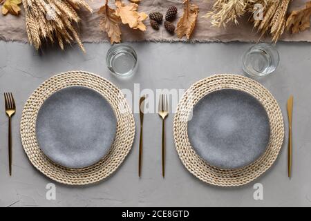 Autumn table setting with dry yellow oak leaves, fall decoration and golden cutlery on grey table. Flat lay, top view. Thankisgiving day Stock Photo