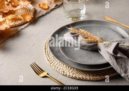 Autumn table setting with dry yellow oak leaves, fall decoration on grey. Thankisgiving day Stock Photo