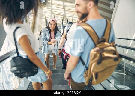 Young happy friends standing on elevator in airport Stock Photo