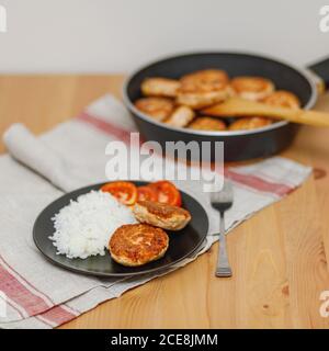 Plate with homemade salmon fish cutlets with rice on wooden table. Healthy food Stock Photo