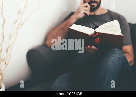 close-up of caucasian man relaxing on sofa at home reading a book Stock Photo