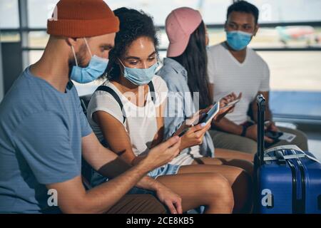 Young cheerful African woman showing screen mobile for bearded man sitting near her Stock Photo