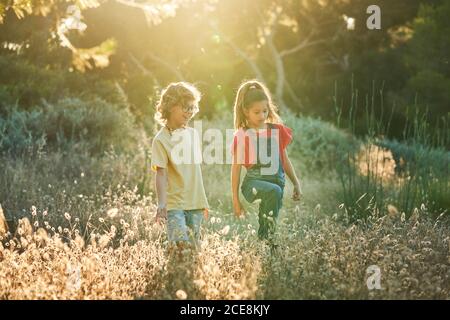 Ten-year-old boy and girl friends walking through the countryside on a sunny summer day in T-shirts and jeans