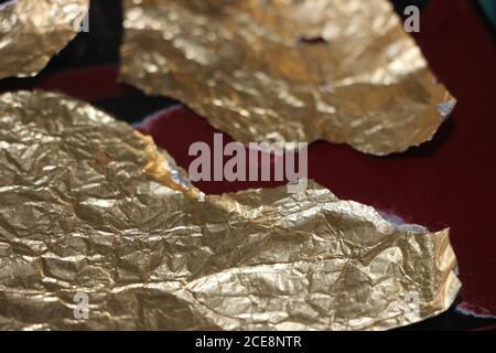 Crumpled and torn golden bronze shiny foil texture background Stock Photo