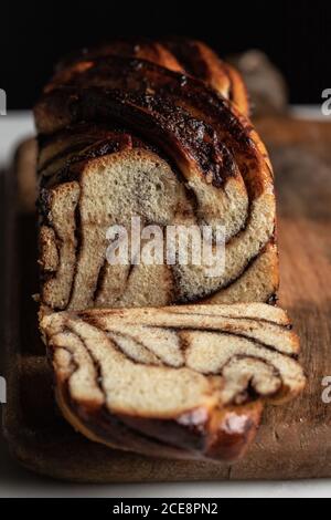 Delicious homemade bread with chocolate and banana babka flavor placed on wooden table in kitchen on black background Stock Photo