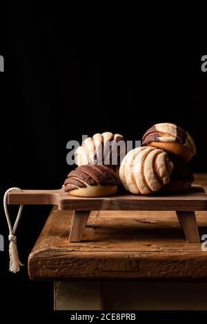 Freshly baked traditional concha bread placed on wooden cutting board on black background Stock Photo