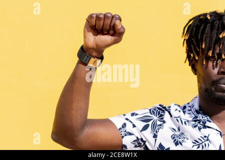 attractive young black man with raised fist on an intense yellow background, concept of human rights struggle and lifestyle, copy space for text Stock Photo