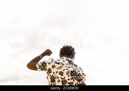 view from the back of a stylish young black man with his fist raised and the sky in the background, concept of freedom and struggle for the defence of human rights, copy space for text Stock Photo