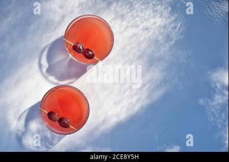 From above of fresh strawberry juice in glasses placed on table and garnished with grape on toothpicks Stock Photo