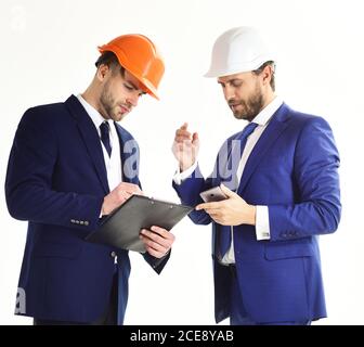 Architect and engineer discuss project. Construction, engineering, business, confidence, architecture, partnership concept. Engineers with serious faces. Business partners look at building plan. Stock Photo
