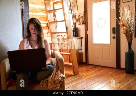 Self employed Woman reading information on netbook while working on startup project at home Stock Photo