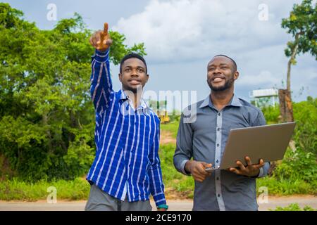 Young African man pointing at some places on farmland for his business partner Stock Photo
