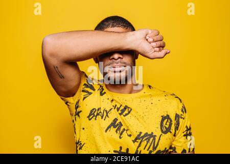 Mixed race young man looking at camera with serious expression over yellow background Stock Photo