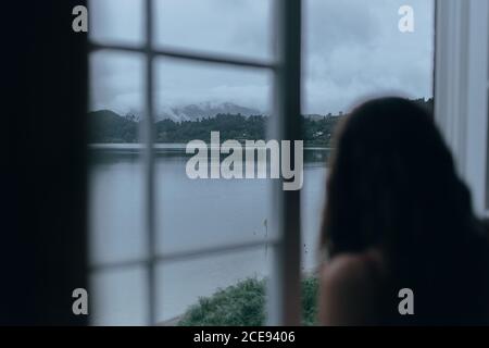 Woman looking through window of room Stock Photo