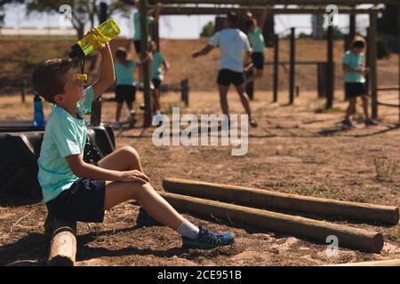 Boy pouring water on his face from a bottle at a boot camp Stock Photo