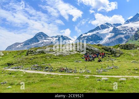A group of mountain bikers on a Transalp tour from Füssen to Lake Como - here on the road in the region of the Passo Bernina Stock Photo