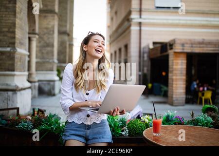 Happy excited woman reading good news on line in a laptop outdoor Stock Photo