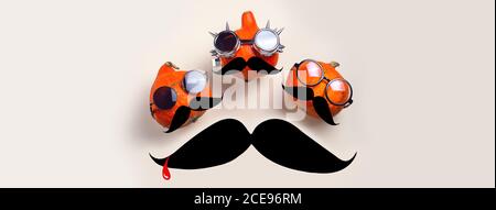 Three orange rocker pumpkins with glasses and a mustache on a light background. Halloween concept. Banner Stock Photo