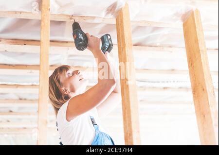 A young woman uses a screwdriver to screw the wood screws into the boards. Stock Photo