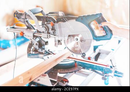 Wood sawing machine. A woman's hand controls the device and cuts the boards. Stock Photo
