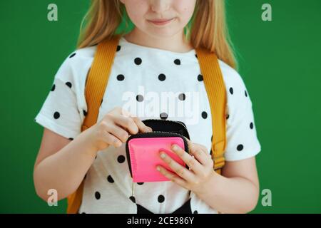 Life during coronavirus pandemic. Closeup on pensive child in white polka dot blouse with yellow backpack and pink mask counting pocket money isolated Stock Photo