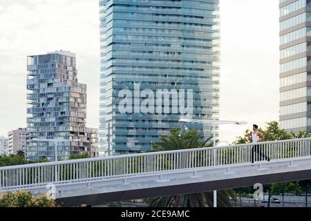 sportsman running on a city bridge in front of buildings, concept of urban sport and healthy lifestyle, copy space for text Stock Photo