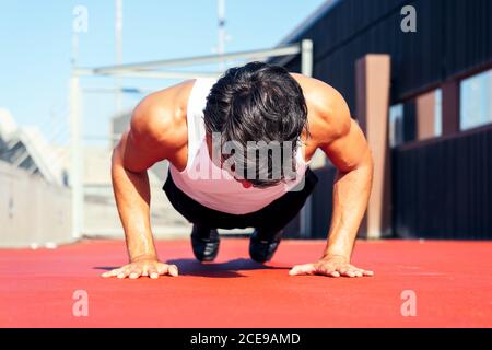 unrecognizable sporty man doing push ups on a red floor, concept of urban sport and healthy lifestyle Stock Photo