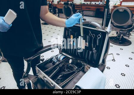 Male caucasian barber at the barbershop wearing gloves preparing working place for client. Professional barber wearing gloves. Covid-19, beauty, selfcare, style, healthcare and medicine concept. Stock Photo