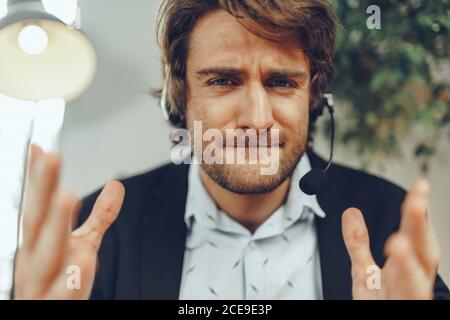 Close up portrait of an angry businessman with headset having stressful online conversation Stock Photo