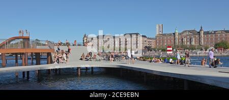 People sunbathing on Kalvebod Waves and the official Islands Brygge Harbour Bath on opposite side of inner harbour canal in Copenhagen on a summer day Stock Photo