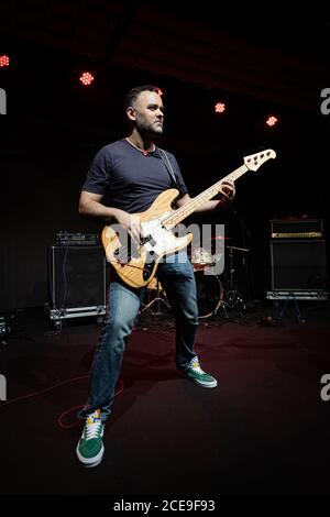 Caucasian Man is Performing on the Stage. Handsome Male Person is Playing on Bass Guitar at Concert. Stock Photo