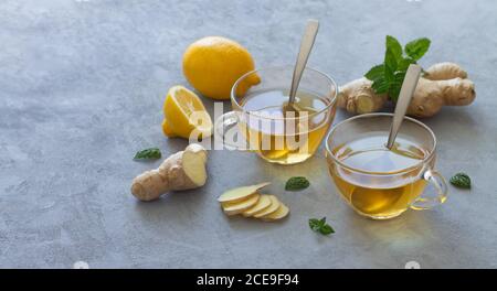 Two glass cups of ginger tea with lemons and mint leaves. Space for text Stock Photo