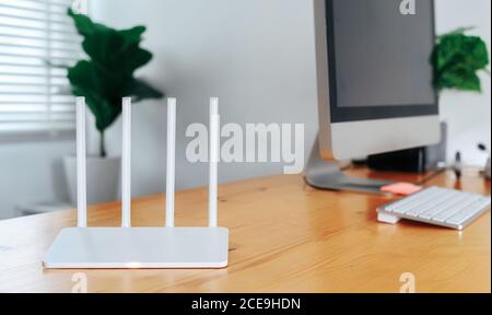 Modern Wi-Fi router on light table in home office Stock Photo