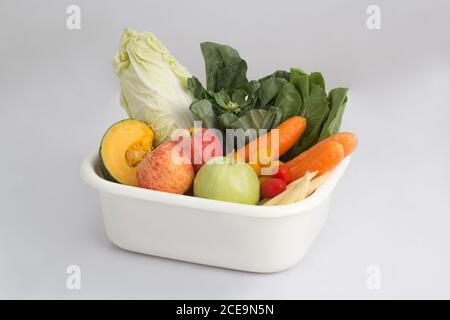 vegetables and fruits in white plastic bowl isolated on white background Stock Photo