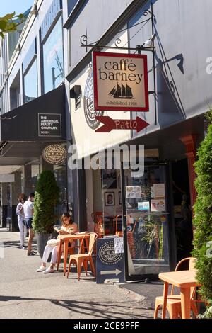 Older woman sitting at a table reading a book outside a cafe on South Granville Street in Vancouver, BC, Canada Stock Photo