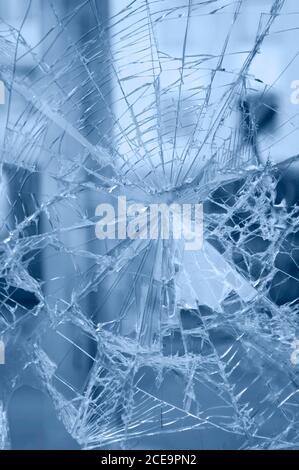 Accident - close-up of broken window. Detail of rifts of cracked glass. Blue background. Stock Photo