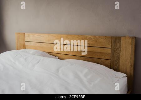 bed with two pillows. white blanket on wood king size bed. minimalism in house Stock Photo