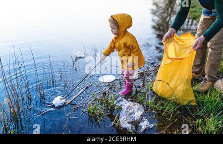 Father with small daughter collecting rubbish outdoors in nature, plogging concept. Stock Photo