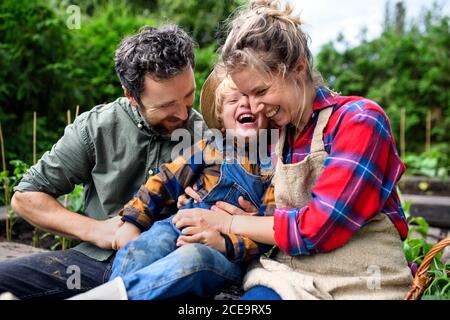 Family with small child having fun on farm, growing organic vegetables. Stock Photo