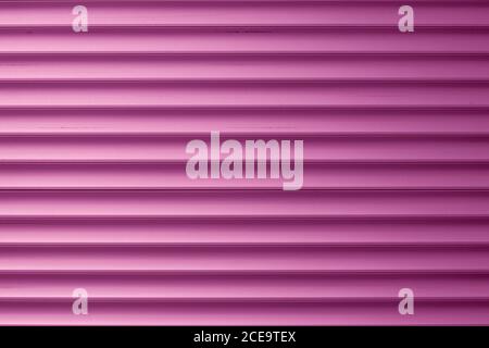 Abstract pink striped background, light metal shutters. Siding texture. Dirty ribbed surface with straight lines. Colored exterior element Stock Photo
