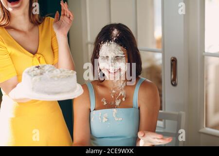 Young woman dip face in white cake with cream. Happy birthday concept.