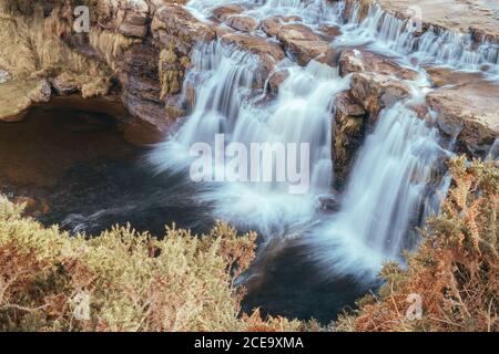 Waterfall on high rocks in autumn Stock Photo