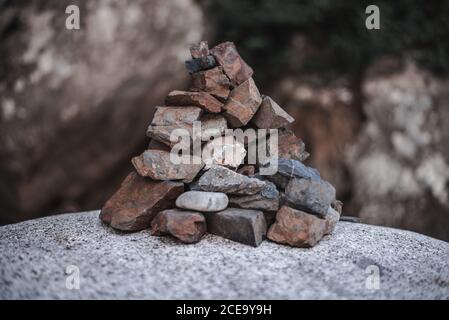 Pile of small rough stones on big rock in nature. Stock Photo