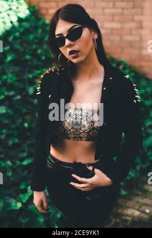 Young lady in crop top and black velvet jacket with silver thorns staying with red lipstick and rings in ears Stock Photo